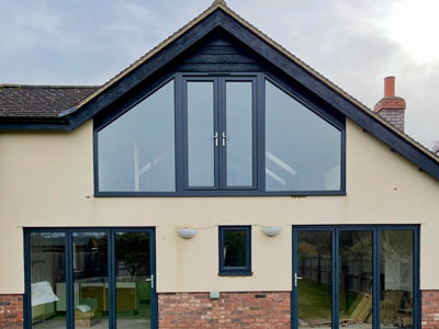 modern house exterior with large windows and a peaked roof design featuring stylish black frames and brick accents