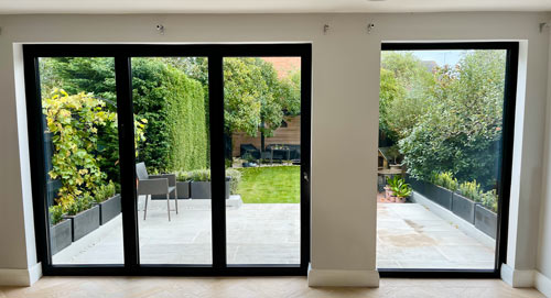 view of a backyard garden through black sliding glass doors