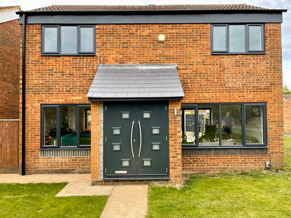 modern brick house with large windows and a distinctive green front door